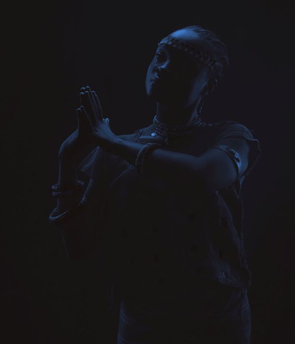 Woman performing a gentle yoga pose in a calm dark environment.